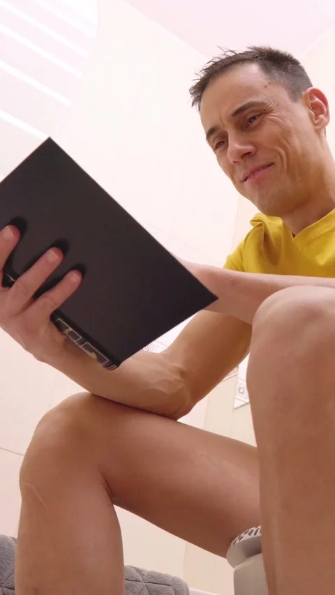 Man reading a book while sitting on the toilet Stock Footage 306569326