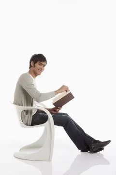 Man reading a book while sitting Stock Photos