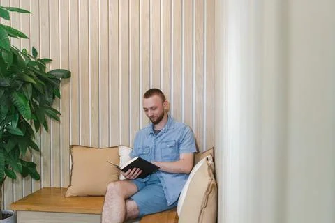 Man reading a book while sitting in a cozy space focused on online educatio.. Stockfoto's
