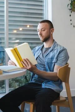 Man reading book while working remotely in bright indoor location during da.. 库存照片