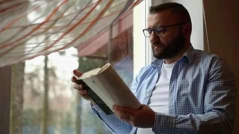 Man reading a book on the window Stock Footage 71658148