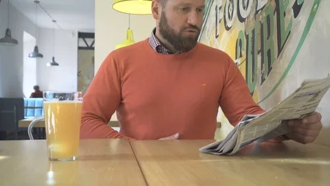 Man reading, browsing, daily newspaper, drink beer, in cafe, indoor, steadicam Vídeos de archivo 73229849