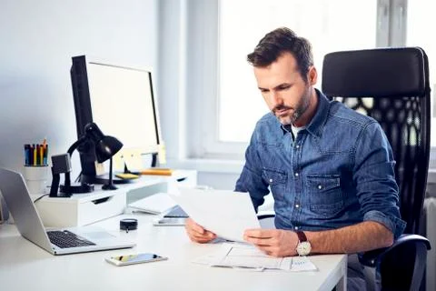 Man reading document at desk in office Fotos de archivo
