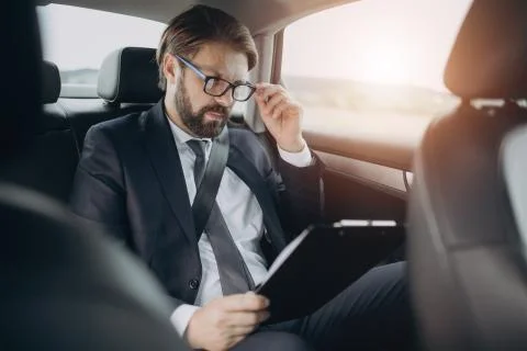 Man reading documents while sitting on back seat at car Stock-Fotos
