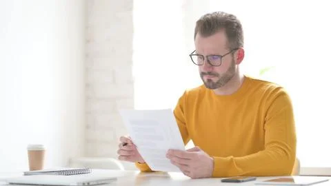 Man Reading Documents while Sitting in Office Stock Photos