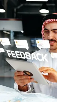 Man reading feedback on a tablet while sitting at a table in a modern office Fotos de archivo