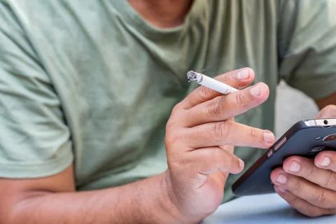 Man reading his phone while smoking Stock Photos