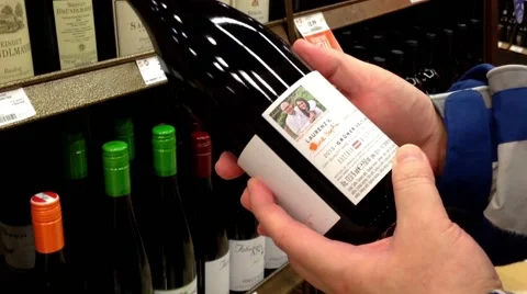 Man reading lable of red wine from the shelf. Stock Footage 48120717