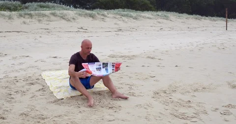 Man reading looking at map on beach Stock Footage 88008046