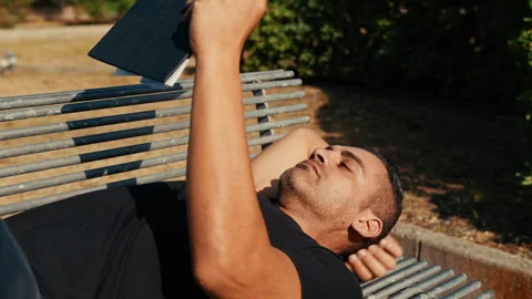 Man reading lying on a park bench Stock Footage 331515804