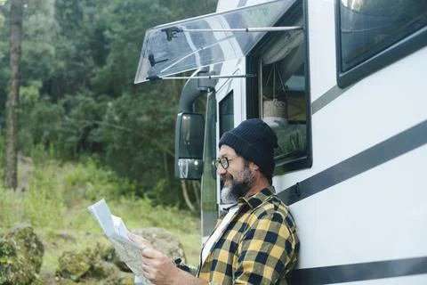 Man reading a map beside his camper van during a relaxed forest road trip Stock Photos