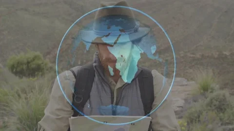 Man reading map in hilly terrain, globe overlay appearing over torso guiding Stock Footage 330540638