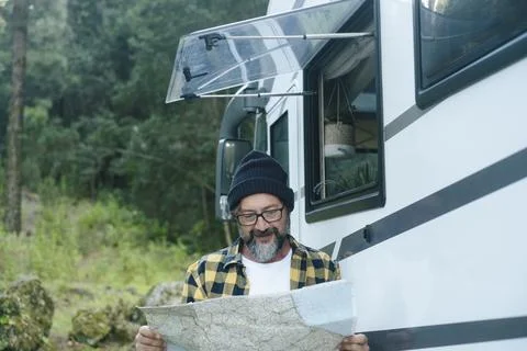 Man reading map next to camper van in forest during relaxed road trip Stock Photos