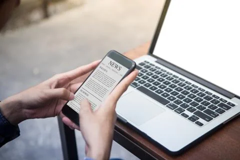 Man reading news article on his smartphone at outdoor cafe Stock Photos