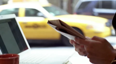 Man reading newspaper and drinking coffee in cafe while using laptop Stock Footage 46159369