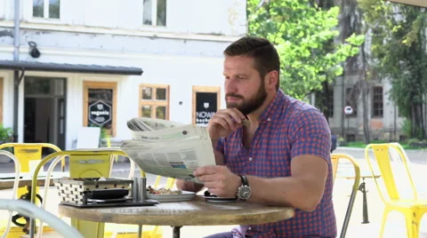 Man reading newspaper during breakfast and looks at camera Vídeo Stock 67628873
