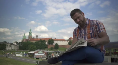 Man reading newspaper on the wall by the river. 库存影片 52696604