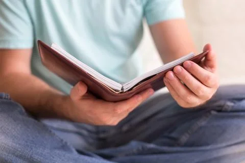 Man reading old hardback note book holding in his hands, on the white couch Stock Photos
