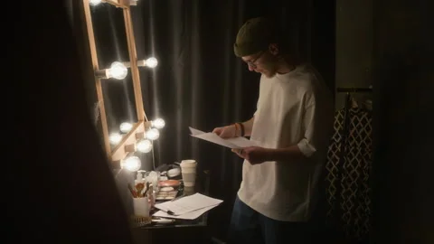 Man Reading Over his Script and Checking Himself in Mirror in Dressing Room Stock Footage 307607791