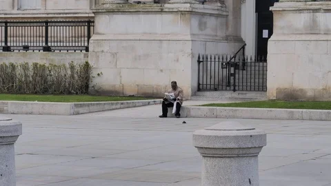 Man reading paper in empty Trafalgar Sq Covid 19 31.03.2020 Video stock 127474927
