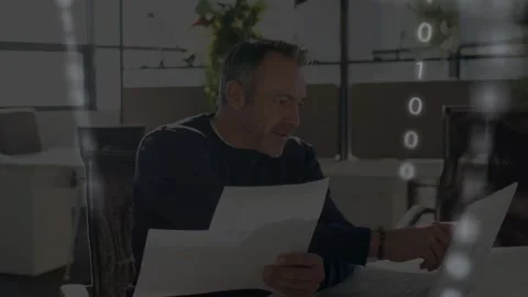 Man reading papers then pointing at laptop, initiating binary overlays while Stock Footage 335762230