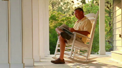 Man reading in rocking chair on back porch 562 Stock Footage