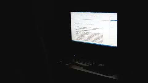 Man reading text at night in a dark room as seen from behind backlit pan uhd 4k Stock Footage 91988172
