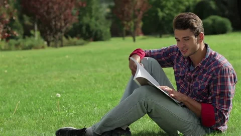 Man reading while sitting on the grass Stock Footage 252680210