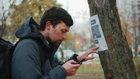 A man reads an advertisement about the loss of a dog in a tree in the park and Stock Footage 319023007