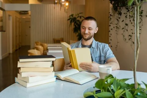 Man reads book in a cafe while preparing for online education in a quiet se.. Stock Photos