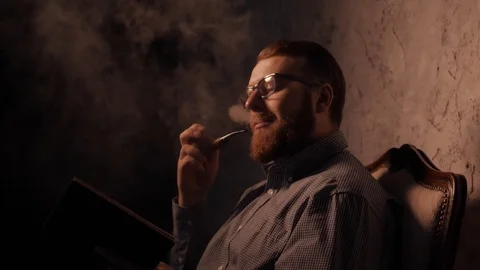 Man reads a book in a dark room and smoking pipe. 4K UHD 動画素材 73362653