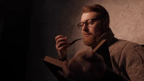Man reads a book in a dark room and smoking pipe. 4K UHD 動画素材 73363010