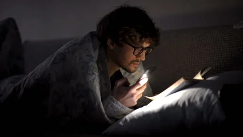 Man reads a book with a flashlight under the covers at night. Stock Footage 169300685