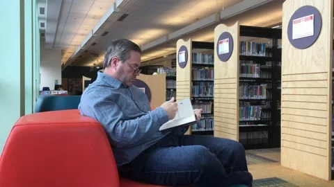 Man Reads Book in Library Video stock 98097318