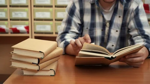 A man reads a book in the library sitting at the table Stock Footage 155884944