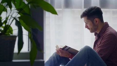 A man reads a book sitting by the window.4 Stock Footage 127664116