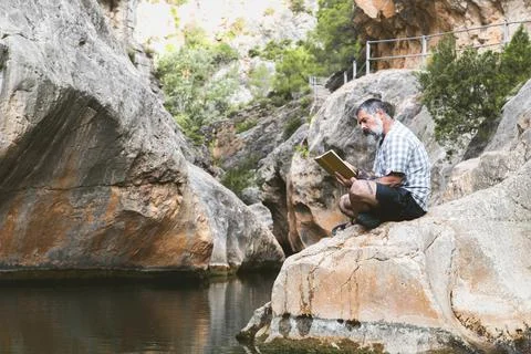 Man reads a book while enjoying the tranquility of the mountain Stock Photos
