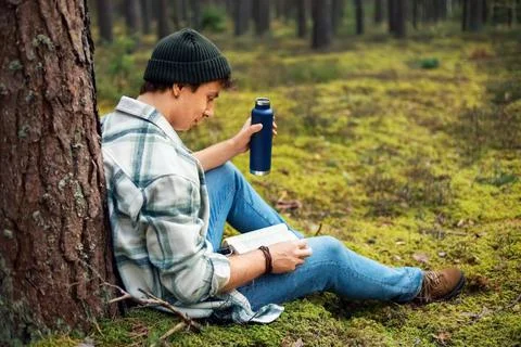 Man reads a book while relaxing in a peaceful forest. This outdoor scene co.. Stock Photos