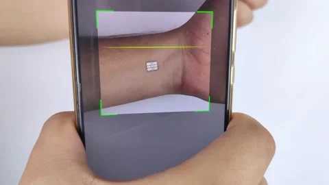 A man reads data using a special device from an implanted chip in a man's hand.  Stock Footage 140716823