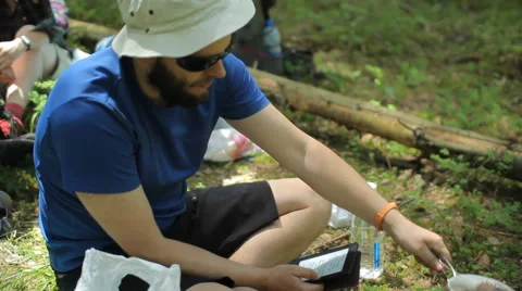 Man reads an e-book in the forest. Near the tourist pot on a gas burner Video stock 64530146