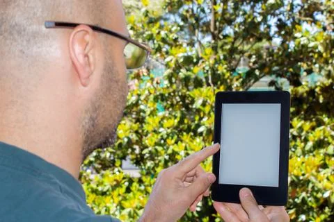 Man reads an e-book in a garden Stock Photos