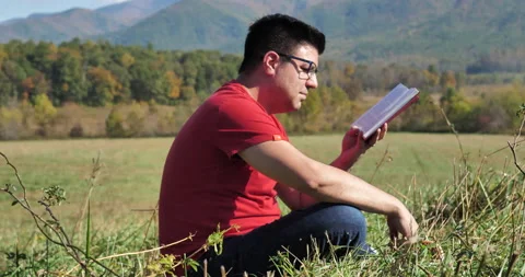 Man reads outside with mountainous background. Stock Footage 142032058