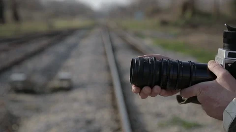 MAN READY TO SHOOT WITH VINTAGE CAMERA AT RAILWAY STATION Stock Footage 102860499