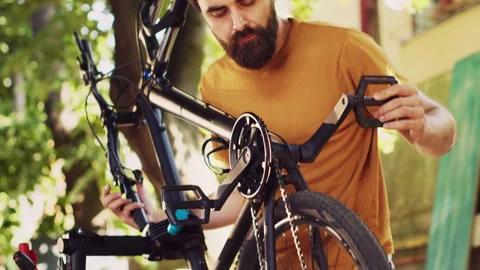 Man realigning bicycle pedals in yard Stock Footage 249286562