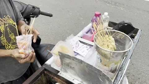A man receives 5 egg rolls, a traditional Indonesian snack. Stock Footage 231429844
