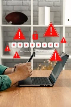 Man receiving scam message on phone while using laptop at home during daytime 库存照片