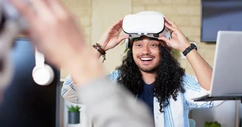 Man receiving virtual reality headset from co-worker and exploring immersive Stock Footage 345063050