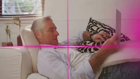 Man reclining on sofa tapping touchscreen to check tech feed, magenta graphics Stock Footage 334694060