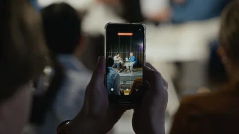 Man Recording Book Presentation on Smartphone at Live Event Stock Footage 338053459