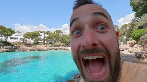 Man recording himself with mobile next to turquoise sea Stock Footage 268230320